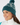 Teal women’s knit golf beanie with white pattern, ribbed cuff and pom-pom, shown on a model.