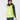 A woman wearing a bright neon yellow-green zip-up puffer golf vest over a navy long-sleeve top and navy leggings, with a navy knit beanie.