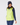 A woman wearing a bright neon yellow-green zip-up puffer golf vest over a navy long-sleeve top and navy leggings, with a navy knit beanie.