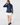 Navy women’s long sleeve quarter-zip golf pullover paired with a white golf skort and navy socks.