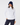 A woman wearing a white quarter-zip golf pullover paired with navy pants and a navy fuzzy bucket hat.