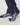 A close-up of a person's feet wearing navy blue socks with a white geometric pattern, paired with dark navy pants.