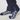 A close-up of a person's feet wearing navy blue socks with a white geometric pattern, paired with dark navy trousers.
