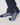 A close-up of a person's feet wearing navy blue socks with a white geometric pattern, paired with dark navy trousers.