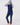 A woman modeling a navy blue ribbed knit vest and matching pants, layered over a light blue long-sleeve top, wearing a light blue knit beanie.