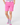 A model is shown from the waist down wearing bright pink golf shorts, a white belt, patterned ladies golf socks, and a patterned top.