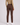 A model shown from the back wearing slim-fit brown golf trousers, a patterned long-sleeve top, and white trainers.