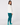 A woman wearing a white long-sleeve golf top, teal sweatpants, and matching teal socks, shown from the back.