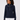 A woman wearing a navy blue ribbed knit sweater with a mock neck and gold zipper detail, paired with white pants.