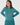 A woman wearing a teal long-sleeve mock neck golf top and matching teal trousers.