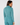 A woman shown from the back wearing a matching teal long-sleeve quarter-zip top and high-waisted trousers with a small white star logo on the upper back.
