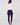 A woman viewed from the back wearing the Natasha white long-sleeve top with a navy blue fitted riding pants.