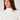 A smiling woman wearing the Natasha ribbed cream turtleneck top.