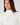 A smiling woman wearing the Natasha ribbed cream turtleneck top.