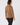 A woman shown from the back wearing a camel brown long-sleeve fleece top and black pants.