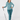 A woman modeling a teal and white patterned long-sleeve button-up shirt, matching teal pants, a headband, and socks, while holding a golf club.