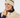 A smiling woman wearing a cream ribbed knit golf beanie with a navy stripe and logo, paired with a matching cream zip-front vest over a navy top.