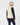 A woman shown from the back wearing a cream ribbed vest over a navy long-sleeve top and navy leggings, with a matching cream beanie featuring a navy stripe.
