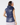 A woman shown from the back wearing a shiny navy sleeveless puffer vest with a high collar, paired with a patterned headband and skirt.