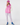 A woman modeling a pink puffer vest, pink knit beanie, white long-sleeve top, white and pink patterned leggings, and blue rain boots.