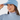 A woman wearing a light blue ribbed knit beanie with a small embroidered logo on the front, paired with a patterned neck gaiter and a matching light blue turtleneck top.