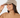 A smiling woman wearing a beige fuzzy knit cap with a small black embroidered logo, paired with a matching tan turtleneck top.