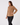 A woman modeling a tan long-sleeve quarter-zip fleece pullover against a plain light gray studio background.