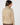 A woman shown from the back wearing a long-sleeve collared blouse with a dense geometric pattern in beige, brown, and white, paired with brown trousers.