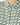 Close-up of a collared button-up shirt with a green, beige, and white geometric interlocking pattern, featuring green buttons.