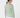 A woman shown from the back wearing a long-sleeve collared blouse with an allover green and white geometric pattern, paired with white pants.