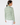 A woman shown from the back wearing a long-sleeve collared blouse with an allover green and white geometric pattern, paired with white pants.