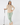 Beige women’s quarter-zip golf pullover paired with green patterned golf leggings and matching headband.