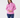 A woman modeling a pink long-sleeve athletic quarter-zip pullover with a white zipper, paired with navy blue leggings.