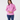 A woman modeling a pink long-sleeve athletic quarter-zip pullover with a white zipper, paired with navy blue leggings.