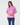 A woman modeling a pink long-sleeve athletic quarter-zip pullover with a white zipper, paired with navy blue leggings.