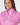 A close-up of a smiling woman wearing a bright pink athletic quarter-zip golf jacket with a white zipper and a colorful geometric patterned trim.