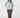 A woman modeling a light blue quilted zip-up vest over a beige patterned long-sleeve top, brown pants, and patterned socks, front view.