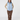 A woman modeling a light blue quilted zip-up vest over a beige patterned long-sleeve top, brown pants, and patterned socks, front view.