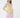 A woman modeling a sleeveless quilted beige golf vest, paired with a light blue ruffled shoulder top, lavender and white patterned skirt and matching headband.