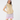 A woman modeling a sleeveless quilted beige golf vest, paired with a light blue ruffled shoulder top, lavender and white patterned skirt and matching headband.
