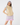 A woman modeling a sleeveless quilted beige golf vest, paired with a light blue ruffled shoulder top, lavender and white patterned skirt and matching headband.