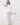 A woman modeling a two-piece loungewear set consisting of a white long-sleeve sweatshirt and lavender polka-dot leggings, holding light purple dumbbells.