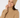 A smiling woman wearing a ribbed knit beige beanie with a small circular star logo patch and a matching beige turtleneck sweater.