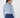 A woman shown from the back wearing a light blue ribbed mock neck long-sleeve top and navy blue pants.