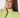 A smiling woman with shoulder-length brown hair wearing a light lime green ribbed mock neck top.