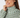 A close-up of a woman wearing a high-neck long-sleeve blouse with a green, white, and beige geometric interlocking pattern.