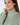 A close-up of a woman wearing a high-neck long-sleeve blouse with a green, white, and beige geometric interlocking pattern.