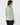 A woman shown from the back wearing a light green and white patterned mock-neck long-sleeve top and black pants.
