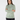A woman wearing a long-sleeve mock neck top with a green and white geometric pattern, paired with black pants.