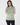 A woman wearing a long-sleeve mock neck top with a green and white geometric pattern, paired with black pants.